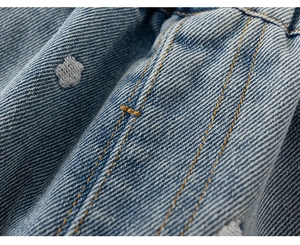 Vista macro del tessuto denim blu con ricami floreali e cuciture gialle a contrasto