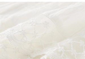 Macro shot of delicate white embroidered lace and floral mesh texture on girl's skirt