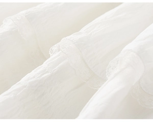 Detailed view of white pleated fabric with delicate lace trim on girls' skirt