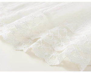 Close-up of white girls' tulle skirt showing intricate hollow floral lace and pleat texture