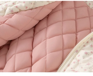 Close-up of pink quilted cotton fabric with floral lining and high-quality white zipper
