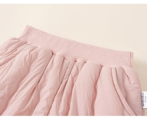 Detailed macro view of girls' pink quilted pants with elastic waistband and woven label