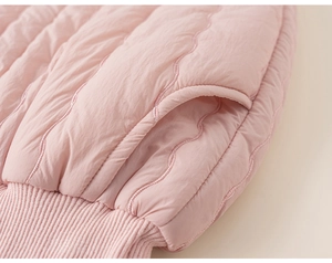 Detail of pink quilted jacket featuring wave stitching and elastic ribbed cuff