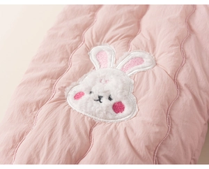 Detailed view of pink quilted fabric with a cute white plush bunny embroidery patch