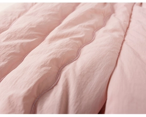 Detailed close-up of pink quilted fabric with scalloped stitching for warm kids' clothing