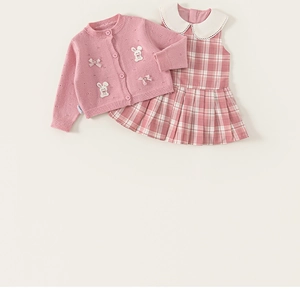 Detailansicht der rosa Strickjacke mit Hasen-Applikation und kariertem Kleid