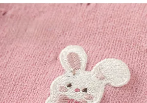 Detail aus rosa Strickstoff mit süßer Kaninchenstickerei und weicher Textur