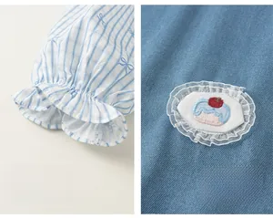 Detail of girl's denim dress showing plaid ruffled cuffs and cake embroidery with lace