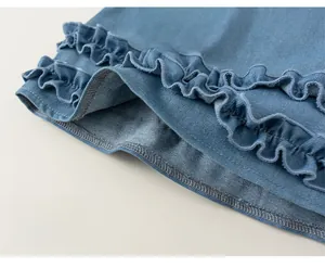 Detailed macro view of light blue denim dress hem with ruffles and bow embroidery