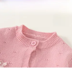 Detail der rosa Strickjacke für Babys mit klassischem Rundhals und Lavendelschleife