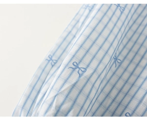 Detail of blue bow print on checkered cotton fabric for girl's denim dress