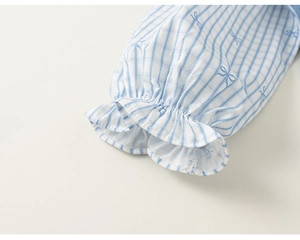 Detail of blue striped girls dress featuring elastic ruffled cuffs and bow patterns