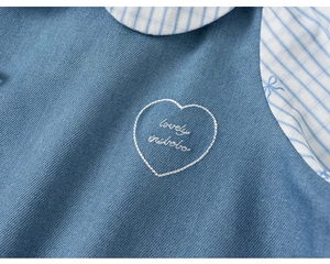 Close-up of heart embroidery and striped Peter Pan collar on blue girls denim dress