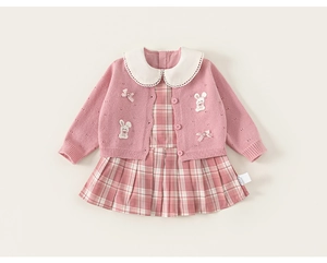 Detail der rosa Strickjacke mit weißem Puppenkragen und kariertem Faltenkleid für Mädchen