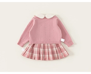 Detail der rosa Strickjacke mit Spitzen-Bubikragen und passendem kariertem Faltenrock