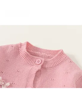 Nahaufnahme der rosa Strickjacke mit zartem Lochmuster und Spitzenblumen-Detail am Stoff