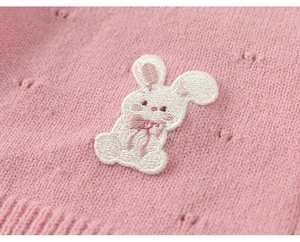 Detail der rosa Strickjacke mit feiner Kaninchen-Stickerei und strukturierten Lochmustern