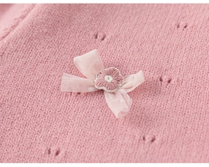 Detailansicht der rosa Strickjacke mit Lochmuster, Tüllschleife und Stickerei-Details