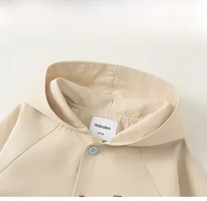 Detailed close-up of beige cotton kids hooded jacket showing buttons and inner brand label