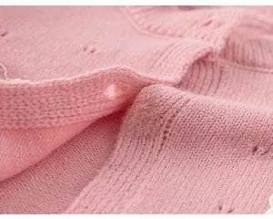Makroaufnahme einer rosa Strickjacke mit Lochmustern und passenden runden Knöpfen