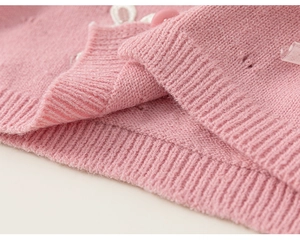 Detail der rosa Strickjacke mit zarter Spitze und gerippter Textur am unteren Saum