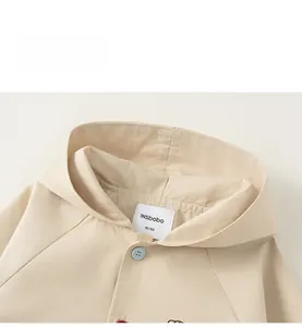 Detail view of the beige toddler hooded jacket showing fabric texture and inner collar label