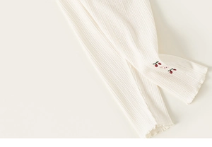 Détail de leggings pour bébé fille avec broderie cerise et tricot de coton côtelé