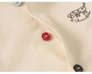 Detail of light beige cotton fabric with colorful buttons and a cute puppy embroidery