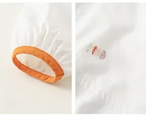 Close-up of children's white hoodie showing orange elastic cuffs and colorful letter print