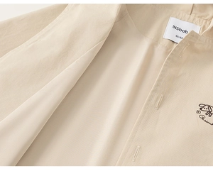 Close-up of boys beige jacket showing fabric texture, INSbob neck label and puppy embroidery
