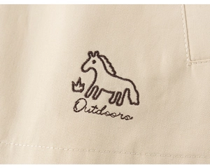 Macro detail of beige cotton twill fabric with brown embroidered outdoors horse motif