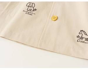 Detailed macro shot of beige twill cotton fabric with a yellow button and animal embroidery