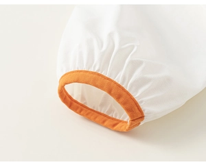 Detailed macro view of high-density white cotton fabric with orange ribbed elastic cuff