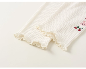 Détail de legging côtelé beige pour fille avec broderie lapin et bords volantés