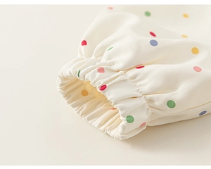 Dettaglio del polsino elastico su una felpa beige per bambini con pois colorati