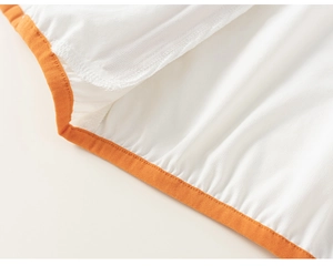 Detail of soft white cotton fabric with professional bright orange stitched edge piping