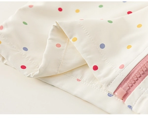 Dettaglio del tessuto a pois colorati con cerniera rosa sulla felpa con cappuccio da ragazza