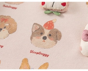 Dettaglio di tessuto in cotone rosa con stampe di cani carini e ricami per bambini