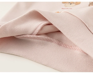 Dettaglio della felpa rosa in cotone con polsini a costine e stampa di cane cartoon