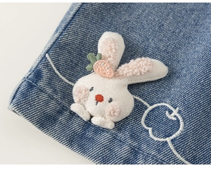 Dettaglio della toppa a coniglio in peluche 3D e ricamo su abiti in denim blu bambino