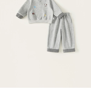 Dettaglio completo di set in maglia grigia per bambini con ricami e patchwork
