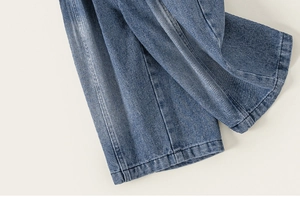 Dettaglio dei jeans blu per bambina che mostra la trama del denim lavato e le cuciture