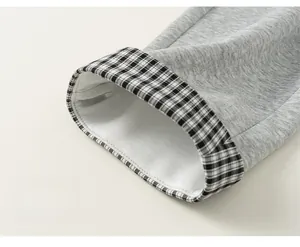 Dettaglio dei pantaloni grigi da bambino con risvolto elegante a quadretti bianco e nero