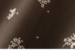 Détail du tissu marron foncé avec motif floral blanc et texture tissée douce