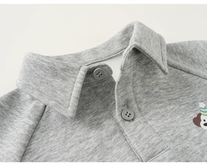 Dettaglio del colletto a polo grigio per bambini con ricamo a forma di cucciolo e bottoni