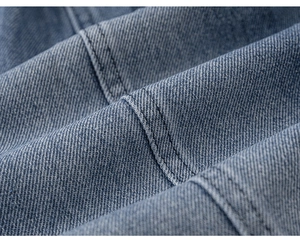 Dettaglio del tessuto denim blu che mostra la trama a saia e la robusta doppia cucitura