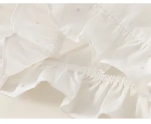 Detail of multi-layered ruffle hem with colorful polka dot pattern on white girl's shirt