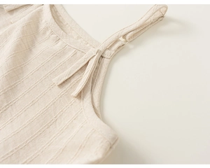 Détail de la bretelle réglable et du tissu texturé sur l'ensemble trois pièces beige