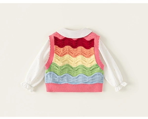 Detail of girls white polka dot shirt with ruffled cuffs and colorful knit vest