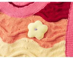 Close-up of colorful wavy knit vest featuring a 3D yellow flower detail with purple bead
